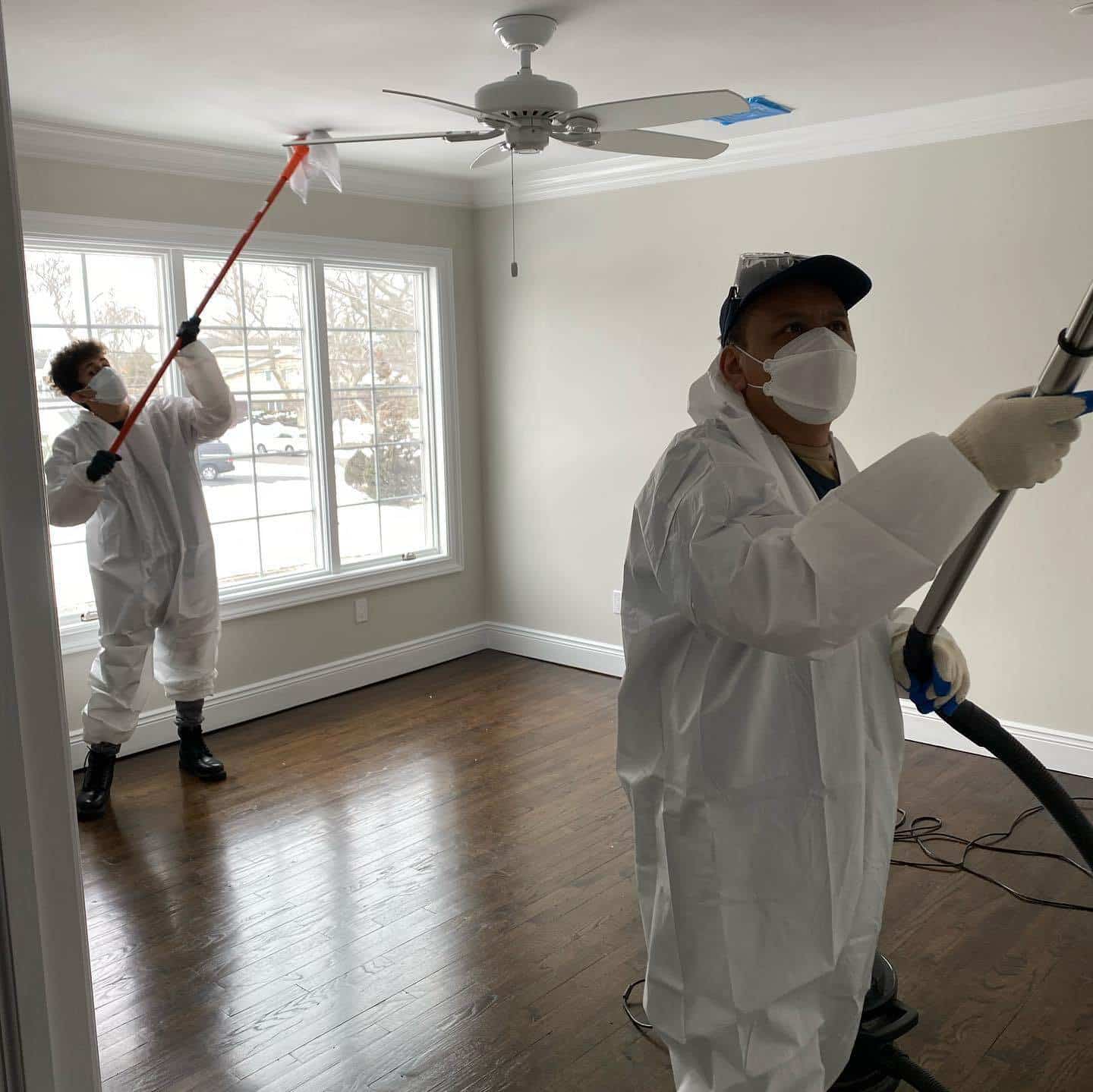 Restoration technicians in protective suits cleaning a room